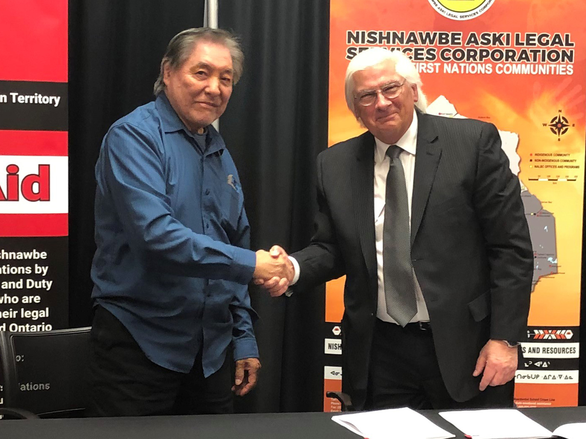 Photo of Jim Beardy, Chair of NAN Legal, and Steve Pengelly, Chair of LAO, shaking hands after signing the agreement.